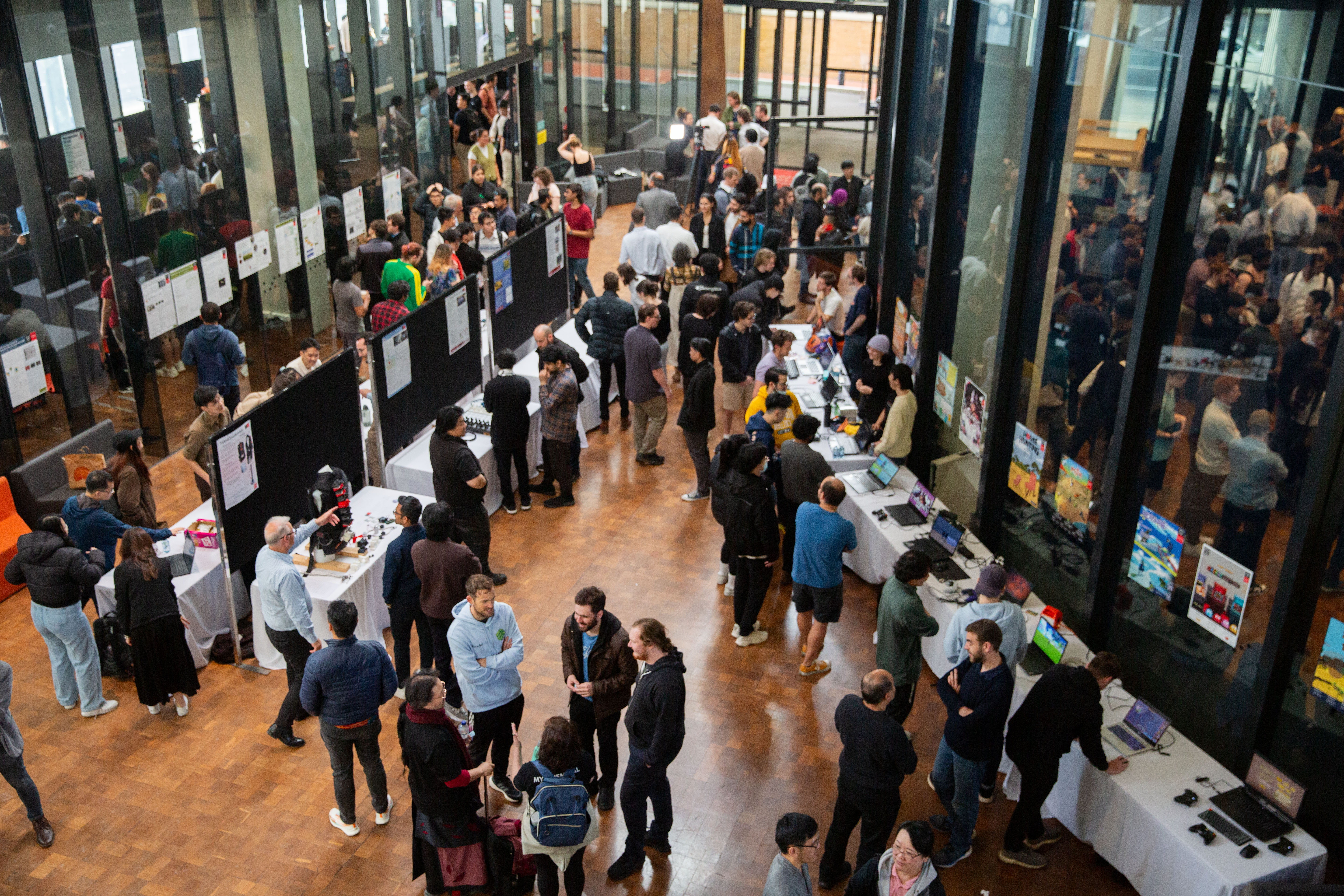 A wide shot of the CapEx event showing people surrounding tables with student projects