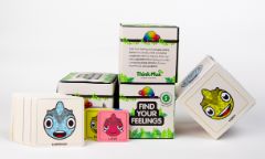 Four Find Your Feelings game packages show different sides. One is inside out to show how the pack folds into a die. In front of them is a series of large and small rainbow chameleon cards. 