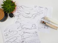 Sketches of fluidly shaped bottle open sit between desk items and a 3d printed prototype and the final design 