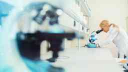 Female scientist looking through a microscope in a scientific laboratory.