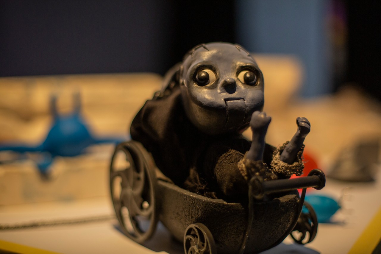 A model of a black cart carrying creepy grey figure is in focus with the background blurred