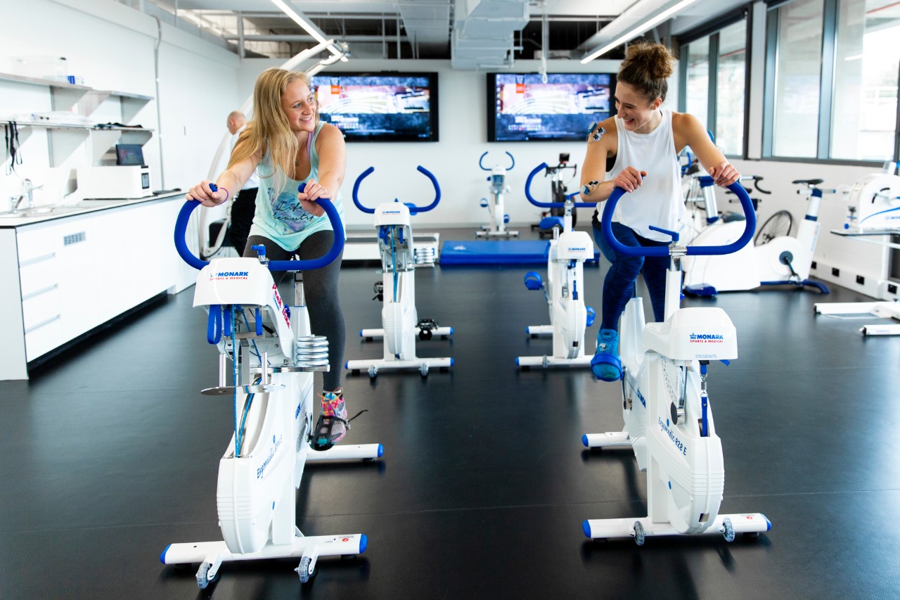 Two female Swinburne students using specialised exercise bikes with monitoring devices attached to their arms