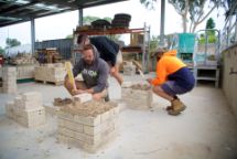 Construction building creating brick columns undercover by 3 males wearing jumpers