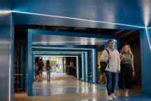 Students walking though the blue hallway underneath the BA building chatting