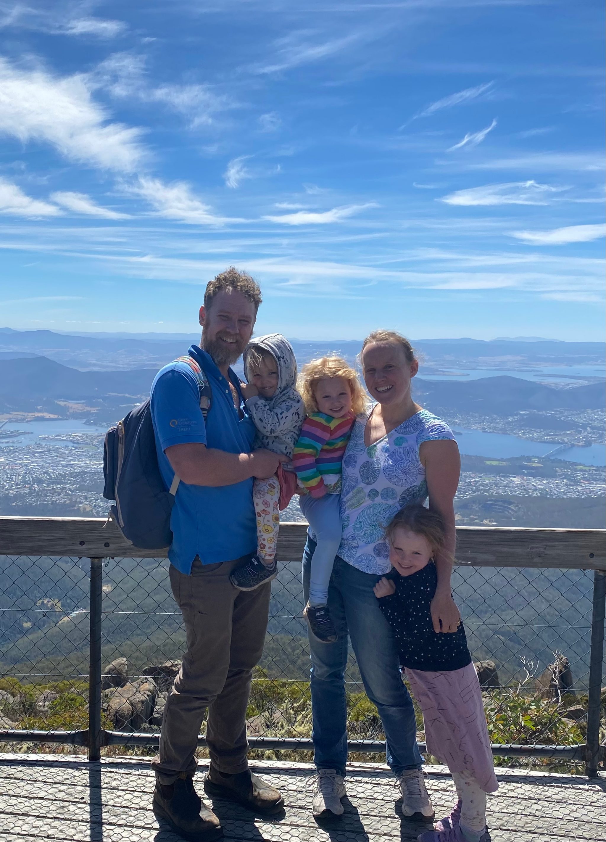 Leonie Suter, her husband and her three daughters stand at the top of Kunyanyi/Mount Wellington overlooking Hobart on a bright, blue-sky day