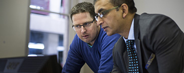 Two Swinburne staff members looking at a computer.