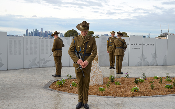 Australian soldier and graphics on perforated memorial panels, and soldiers at the opening