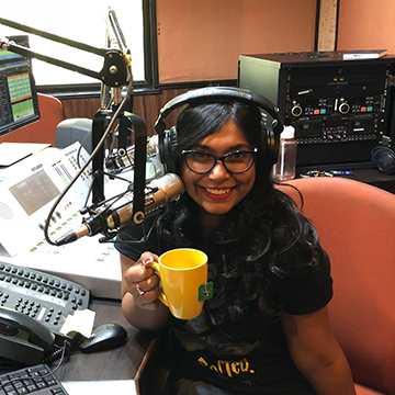 Evita sitting down in her recording studio holding a cup of coffee.