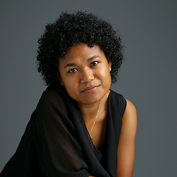 Felismina sitting in front of a plain, dark background.