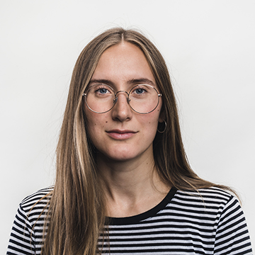Victoria in a black and white striped shirt looking straight ahead with a plain white background.