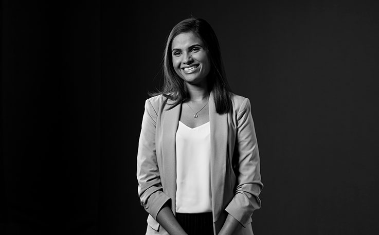 A woman standing and smiling black and white.