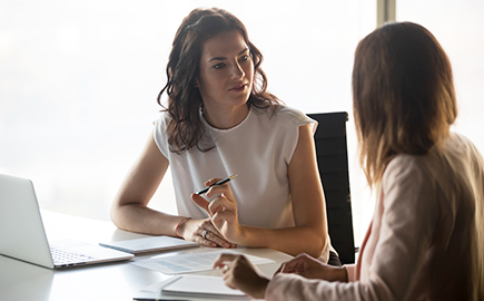 Two ladies talking at a desk